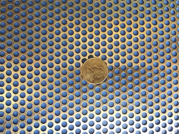 A coin is placed on a aluminum round perforated sheet.