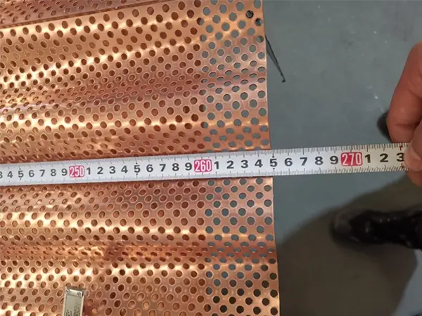 Measure the length of copper architectural corrugated perforated panels with a tape.
