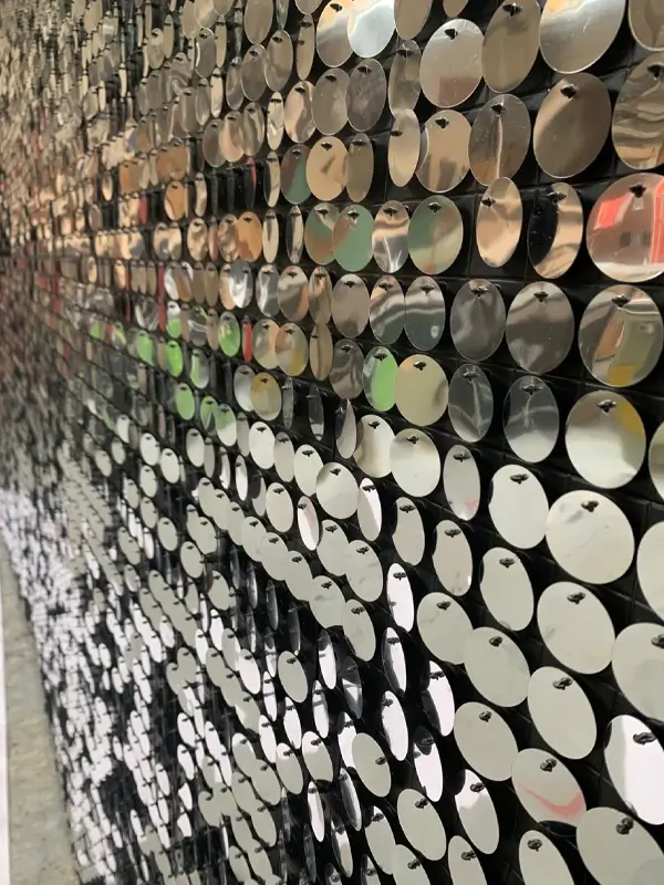 Circular mirrored elements form a wall, installed via back plate mounting.