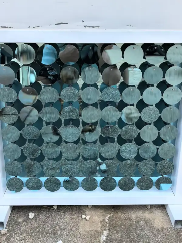 Circular mirrored elements are fixed through back plate mounting, forming a dense and shiny arrangement.