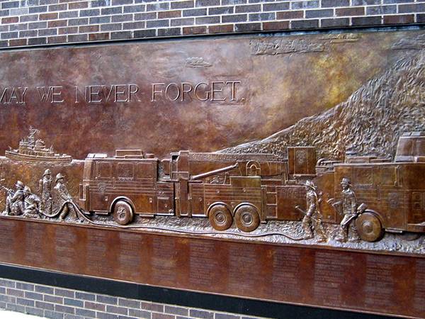 Bronze relief sculpture is installed on the wall of the street.