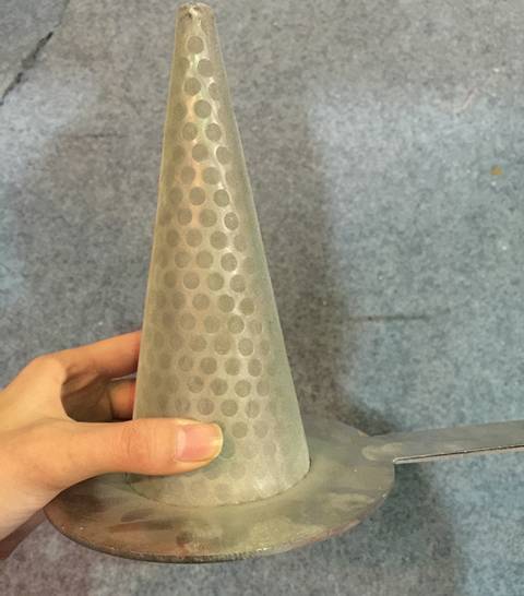 Une main tient un filtre à cône perforé avec un treillis métallique tissé à l'extérieur et une feuille perforée à trou rond à l'intérieur.