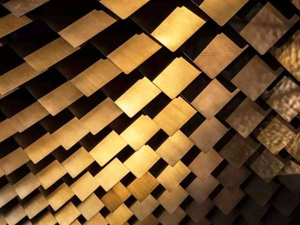 A wall assembled from copper perforated kinetic panels to show off the metallic nature