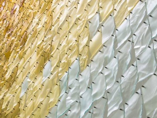 A perforated kinetic facade assembled with yellow and transparent colored wind-activated sheets