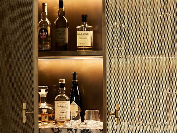 A wine cabinet full of wine with a perforated brass door