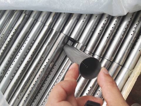 Many perforated tubes are packed in a wooden container.
